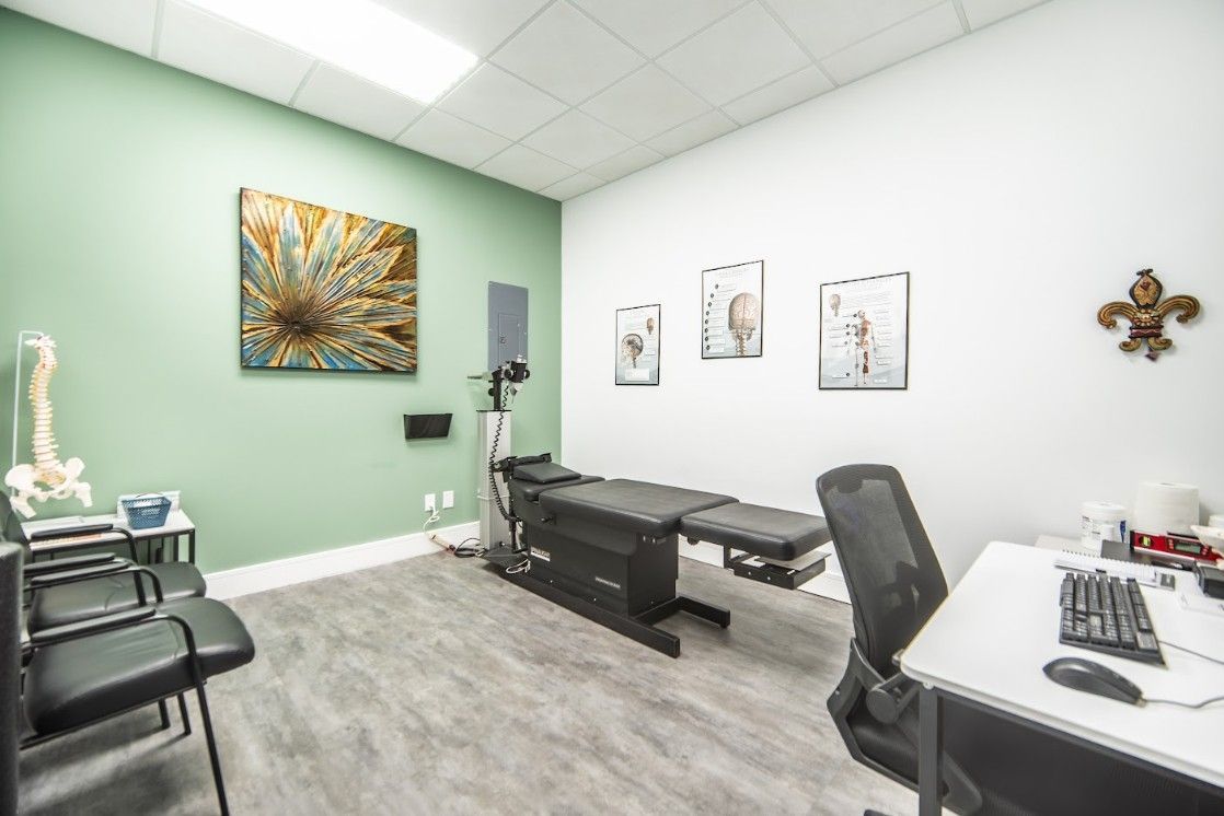 Bright medical exam room with two beds, chairs, desk, wall art, and mint green walls