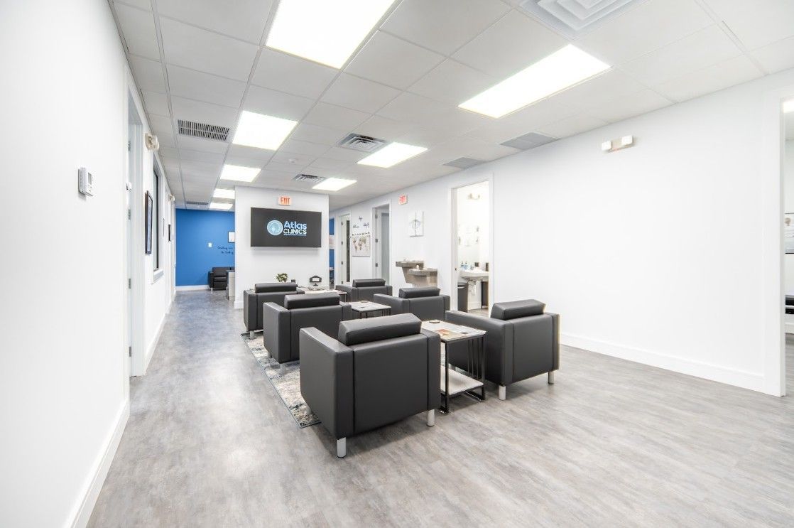 Modern white lounge with black chairs and a wall-mounted TV in a bright office lobby