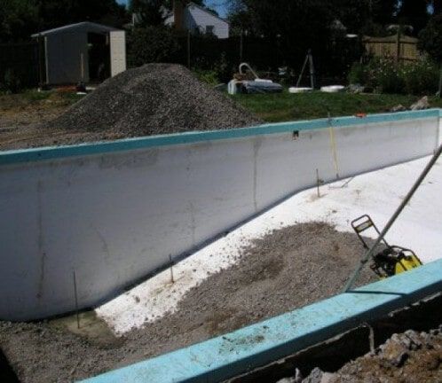 Empty above-ground pool under construction with gravel piles