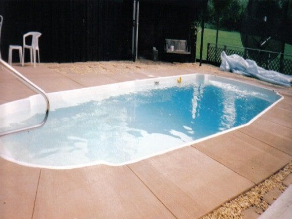 Backyard pool with concrete deck and black fence
