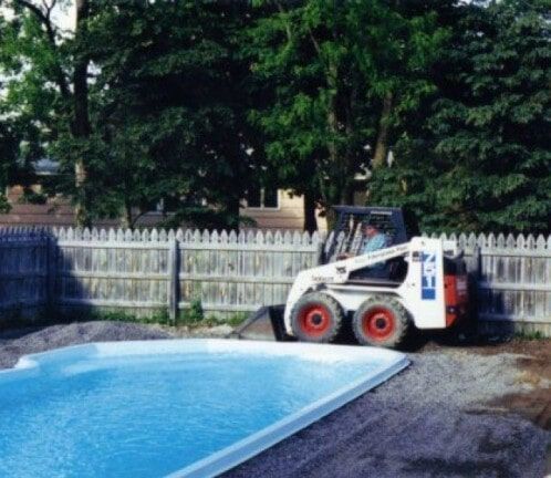Bobcat loader beside a swimming pool