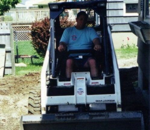 Man seated in a white skid-steer loader