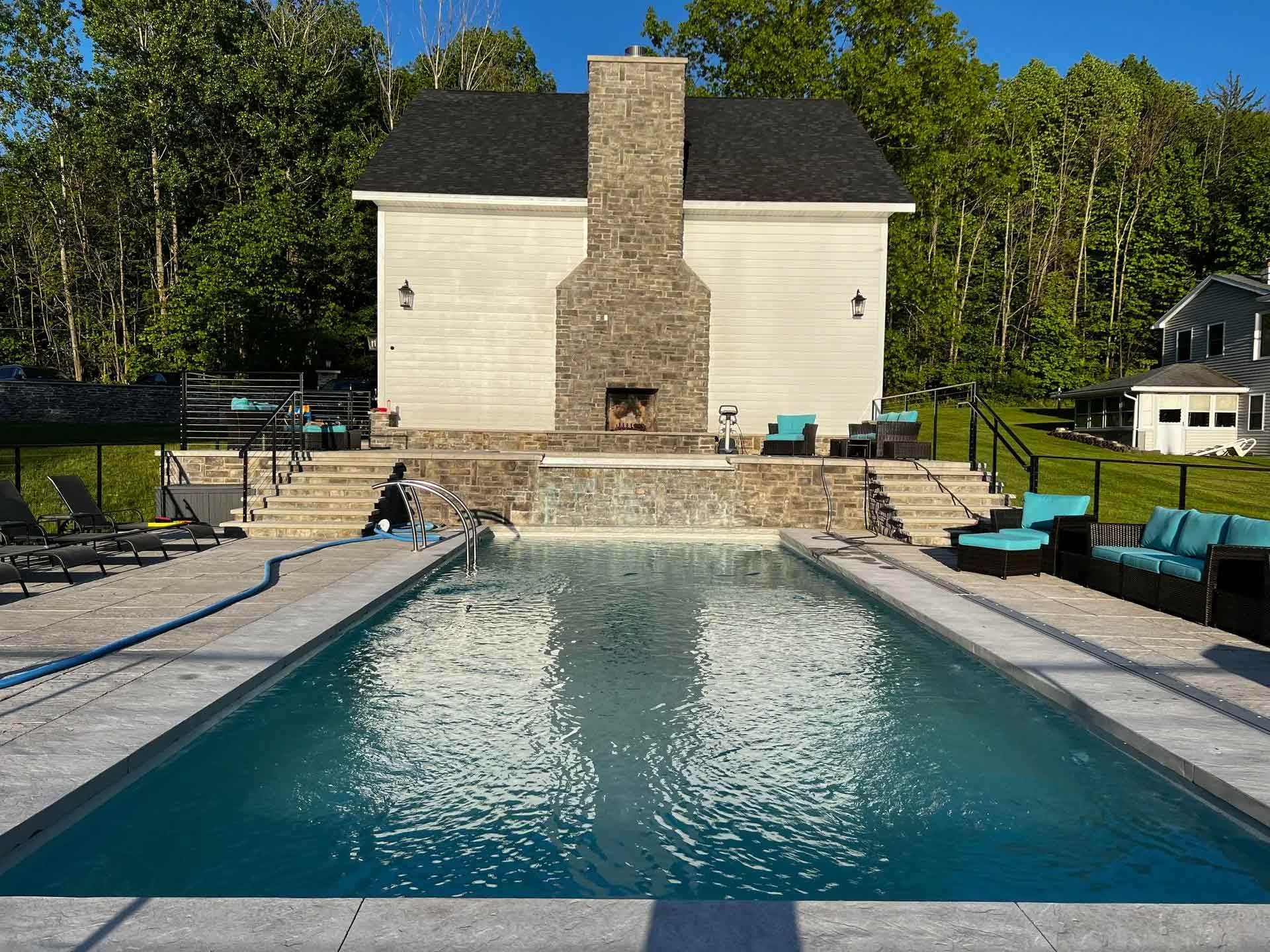 Installed pool with stone patio in backyard