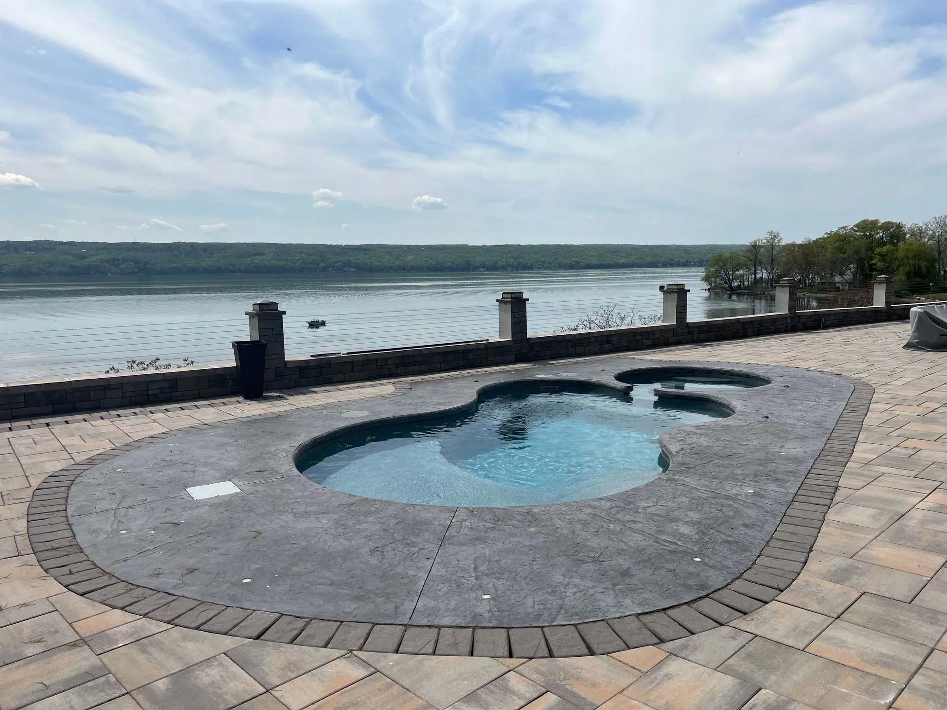 Small round hot tub on a stone patio by a lakeside