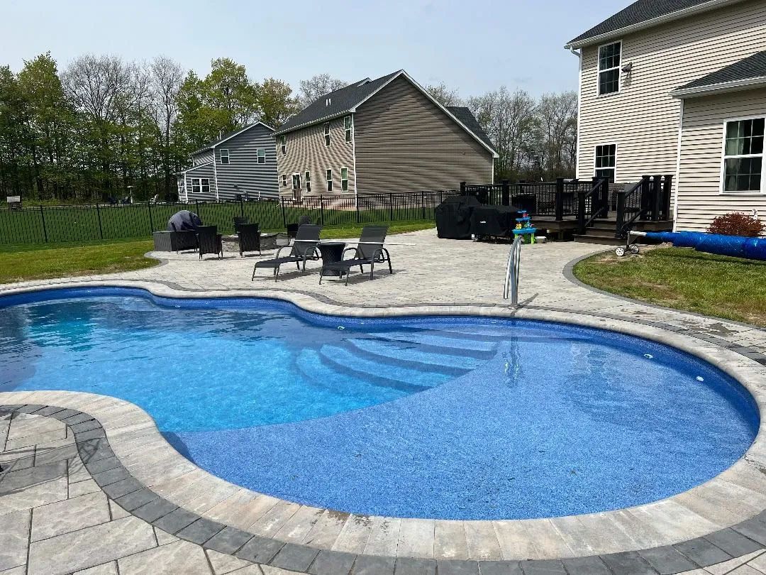 Curved pool with chairs on stone deck