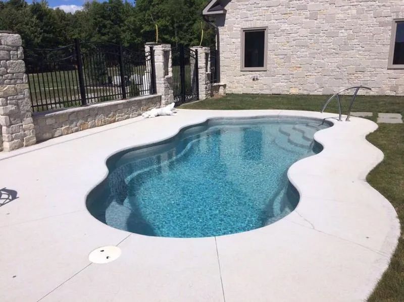 Backyard pool with blue water and concrete deck 