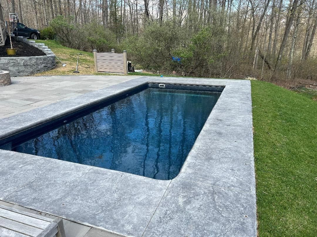 Swimming pool with a concrete deck and green lawn