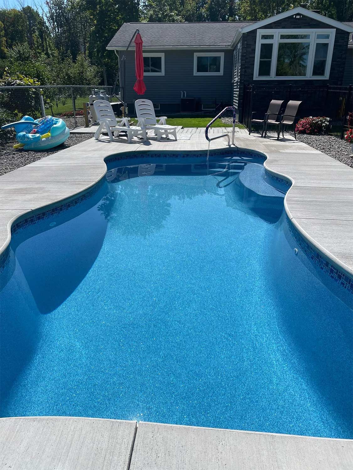 Wide backyard pool and concrete deck