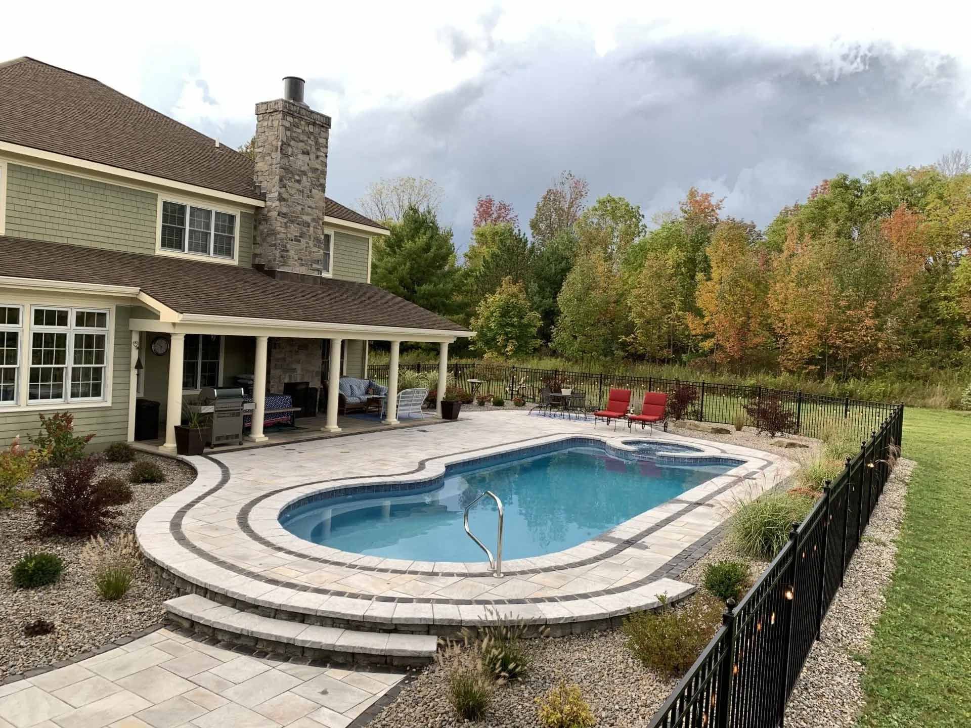 Backyard pool beside a house with a curved deck