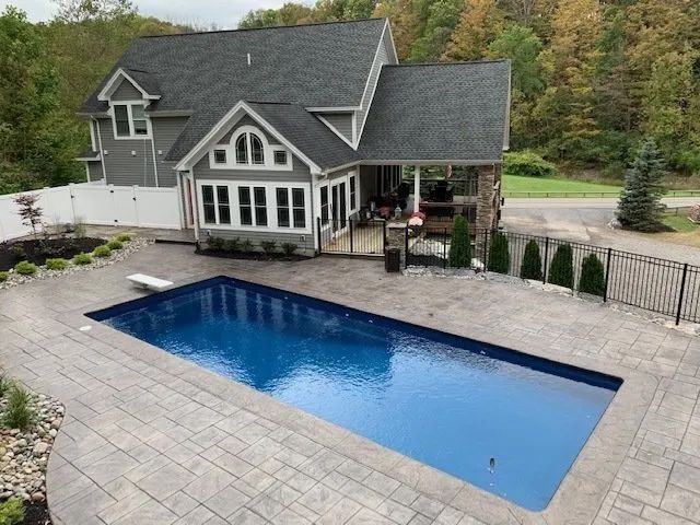 House with a backyard pool and stone patio