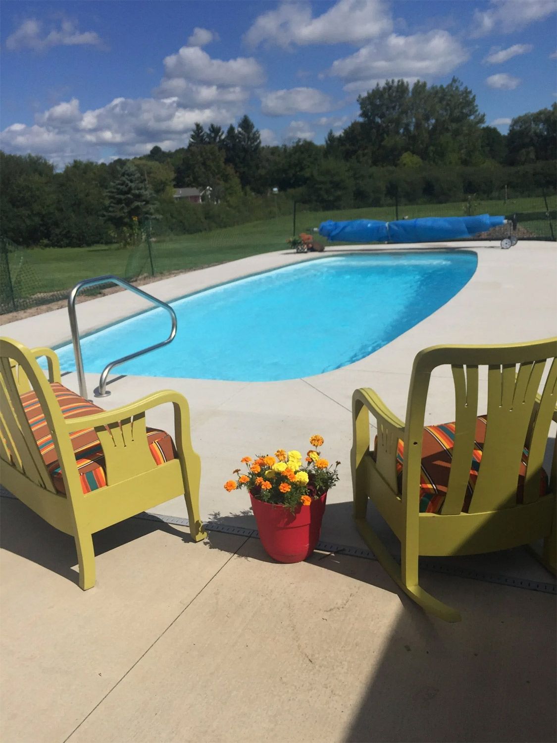 Backyard pool with two yellow chairs