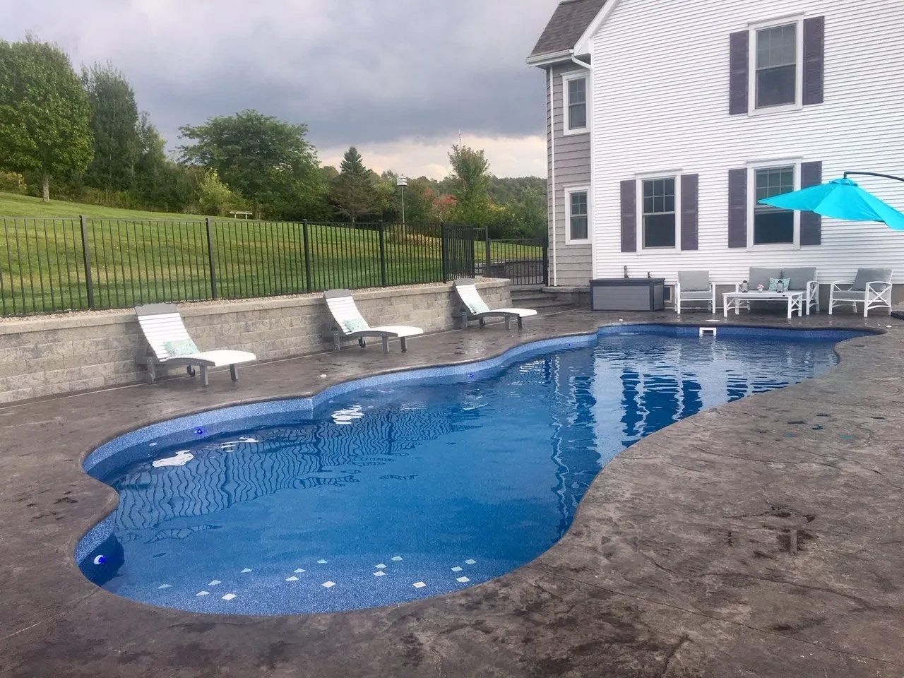 Backyard pool beside a white house