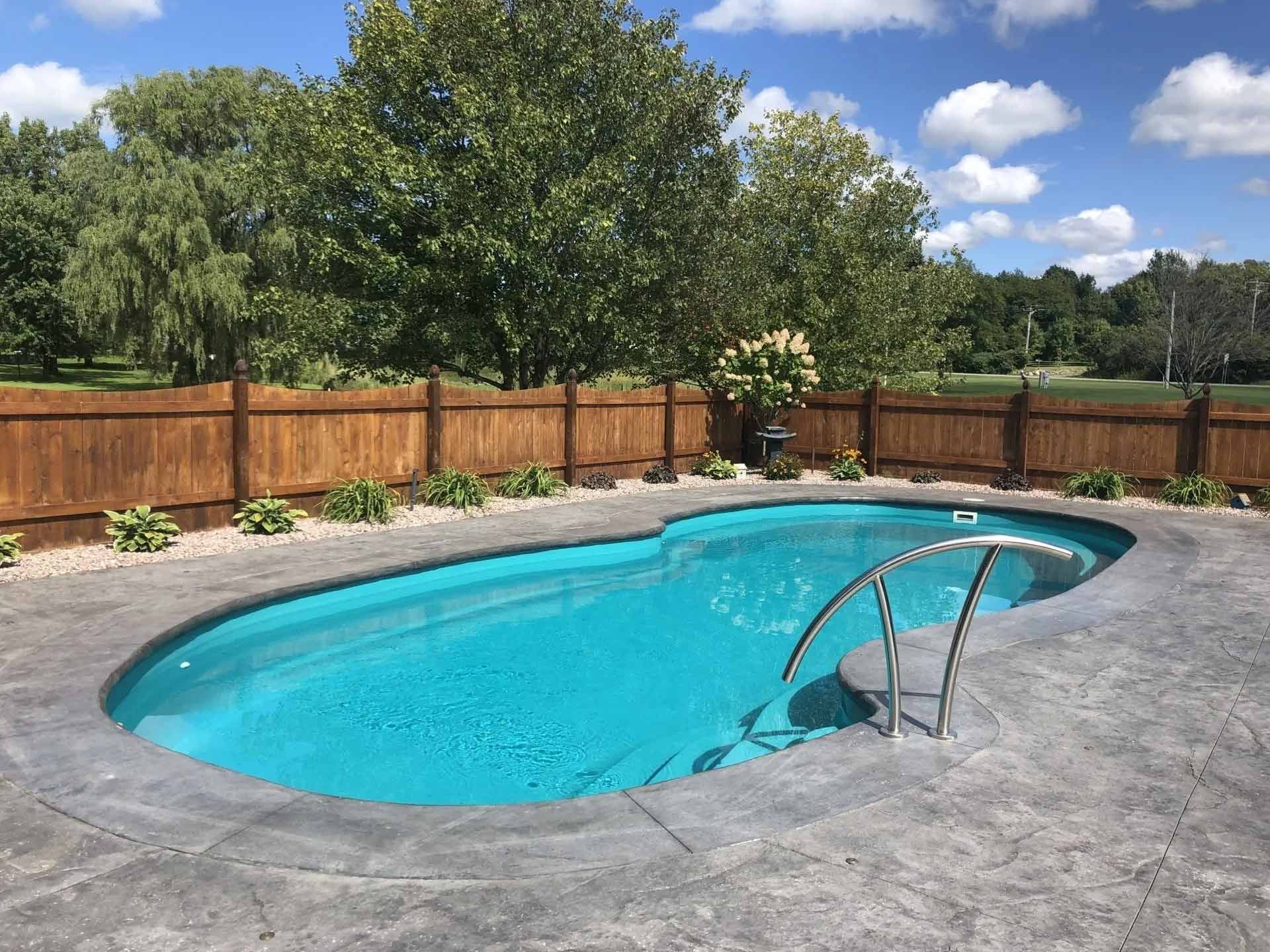 Outdoor pool with concrete patio and wooden fence