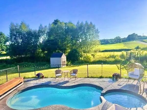 Backyard pool with deck chairs and fence