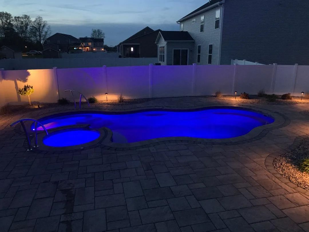 Backyard pool at dusk with blue underwater lights