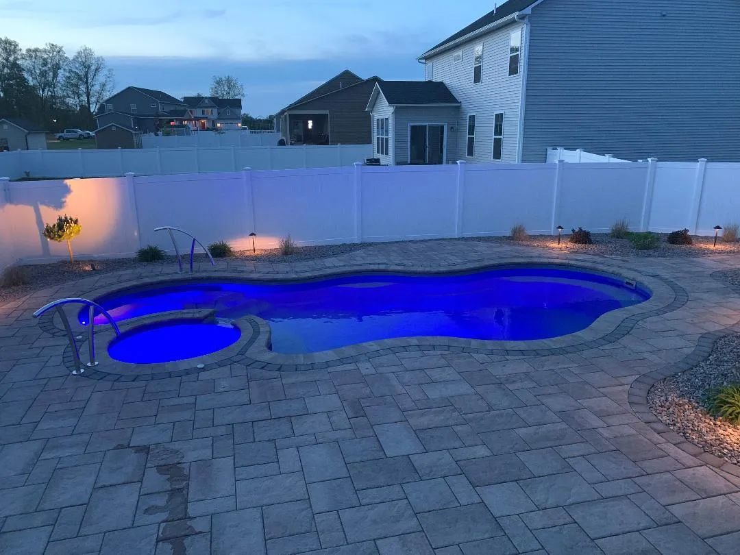 Backyard patio with illuminated blue swimming pool