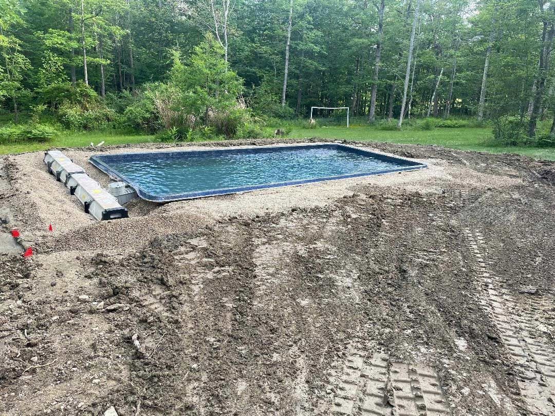 In-ground pool under construction beside a wooded area