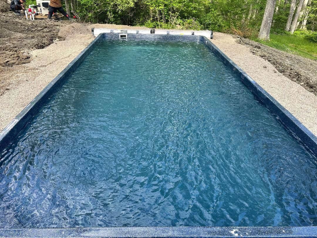Rectangular blue swimming pool with stone edging