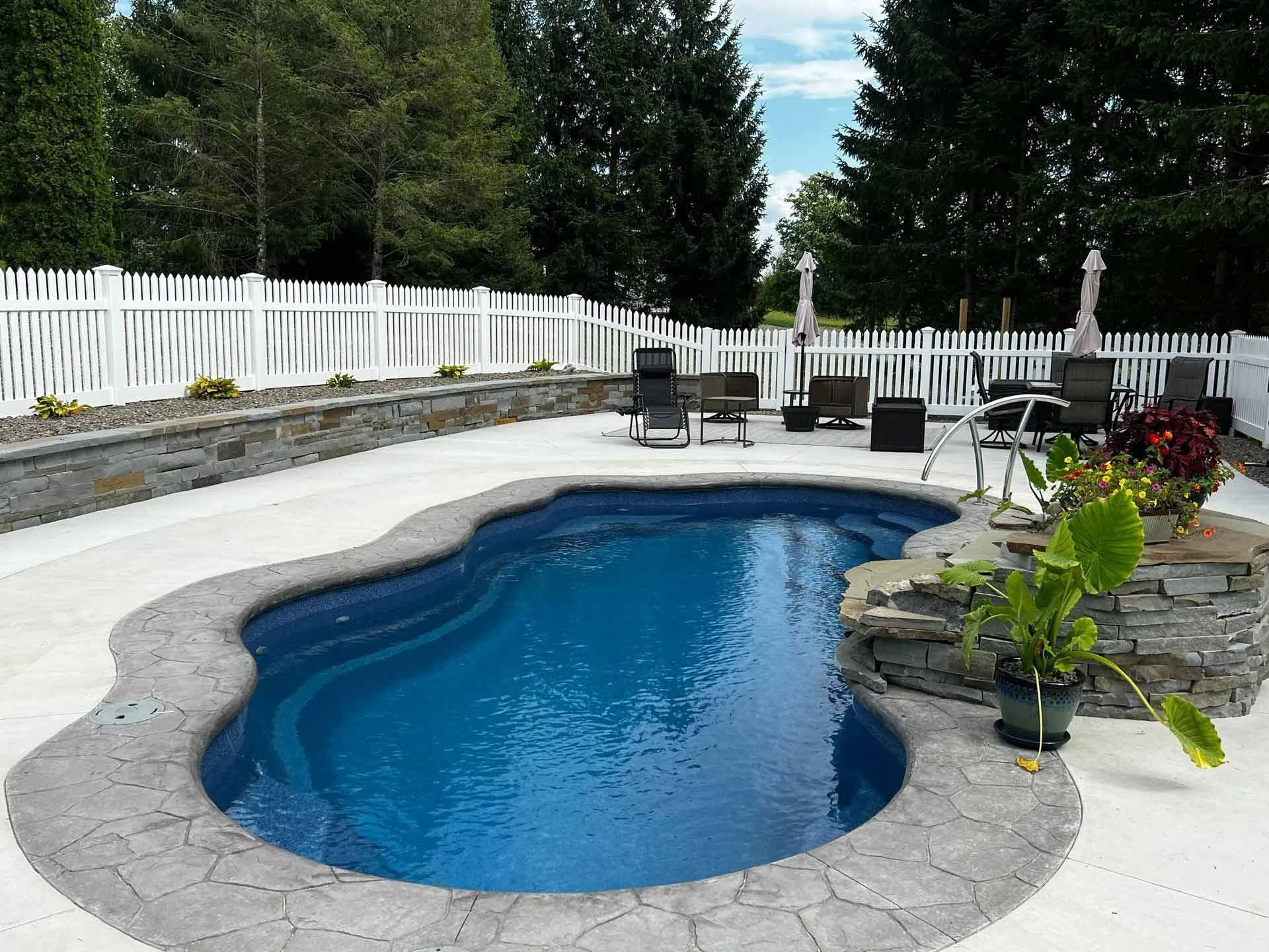 Backyard pool with white fence surrounded by trees