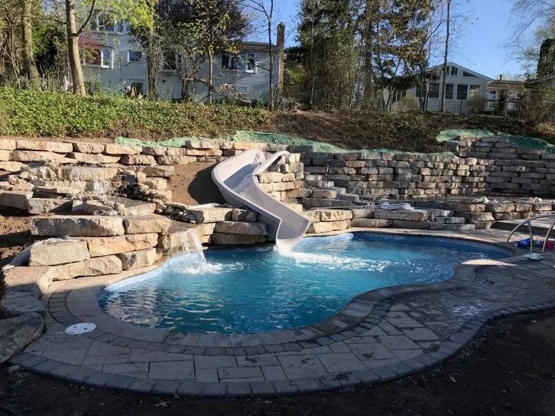 Backyard pool with stone retaining wall and slide