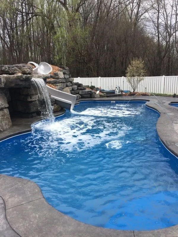 Backyard pool with a rock waterfall and blue water