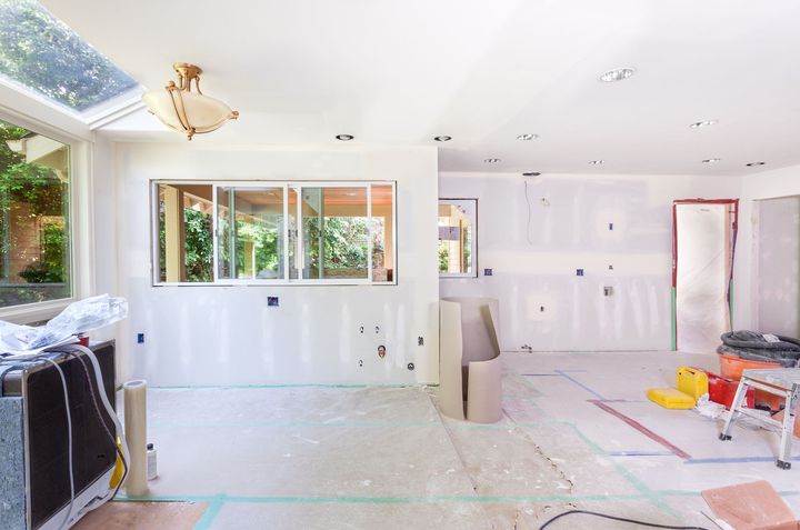 Interior of a room under construction, with drywall on walls and ceiling, window, and unfinished floor.