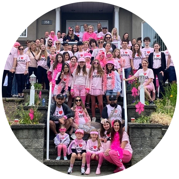 La grande équipe d'Emma, tous vêtus de t-shirts roses assortis, posant devant la maison.