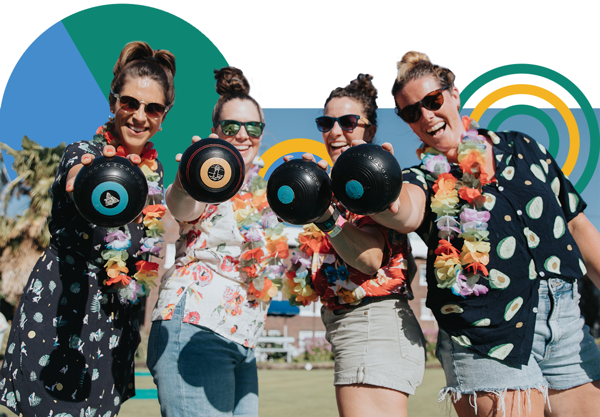 A group of four female bowlers dressed in hawaiaan shirts holding their lawn bowing balls.