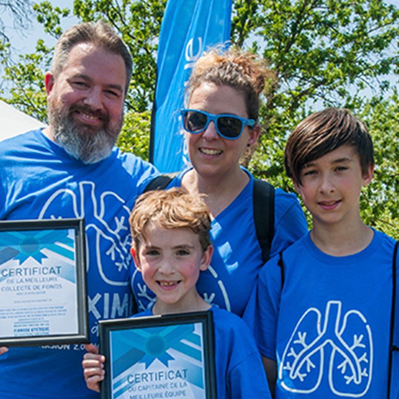 Maman, papa et leurs deux fils brandissent un prix de collecte de fonds lors de l'événement de l'année dernière.