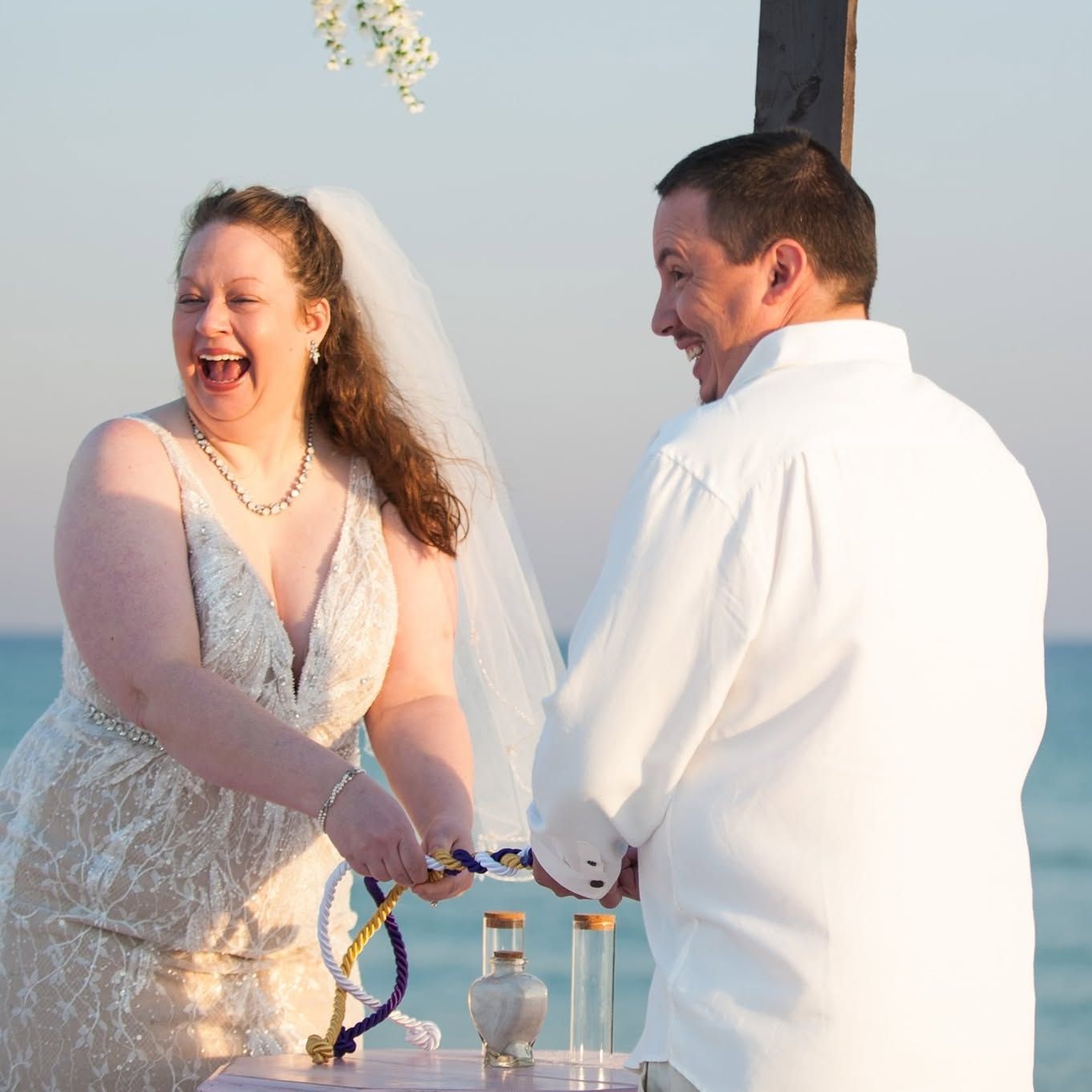 couple holding hands and laughing during beach wedding ceremony