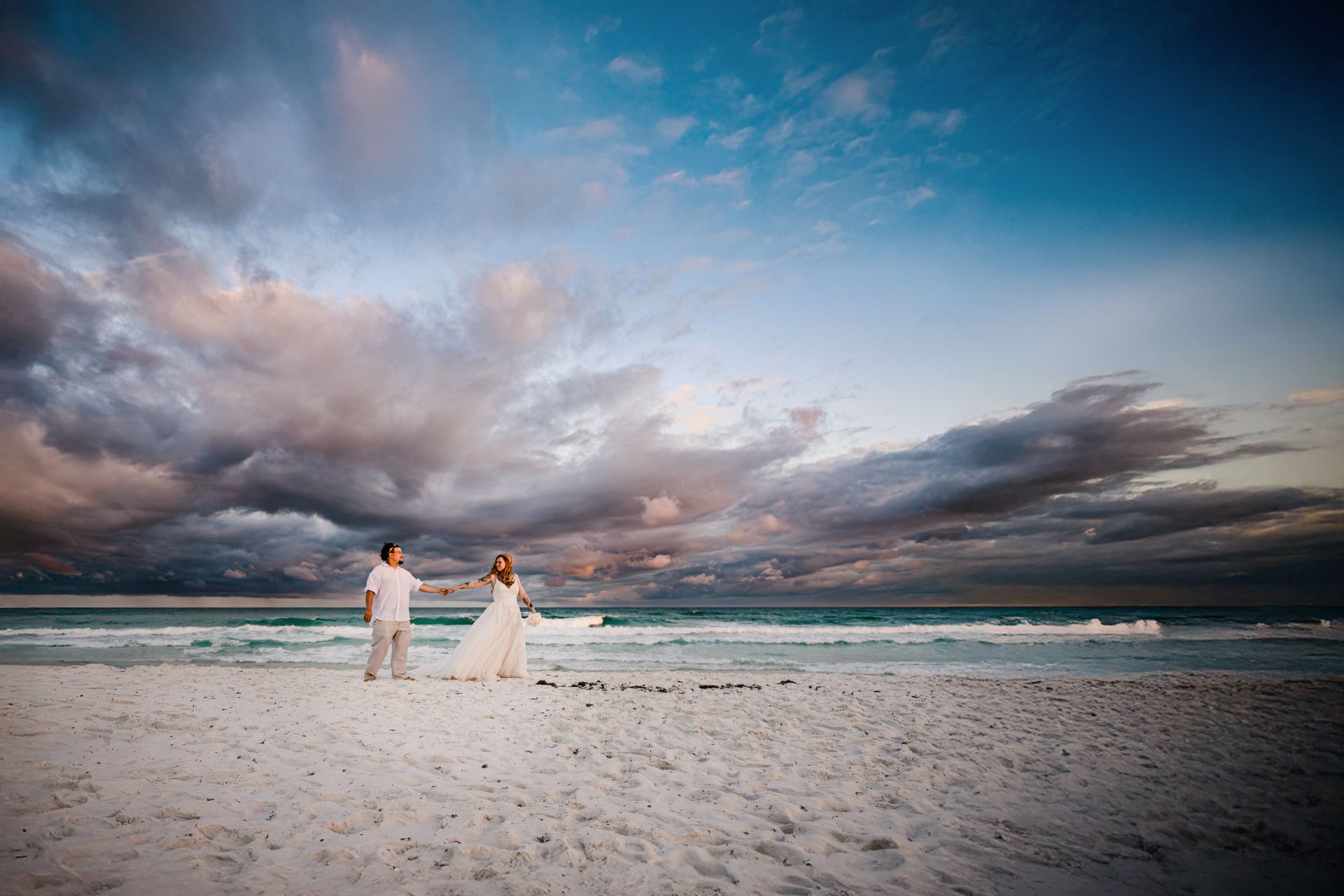 bride and groom holding hands on beach