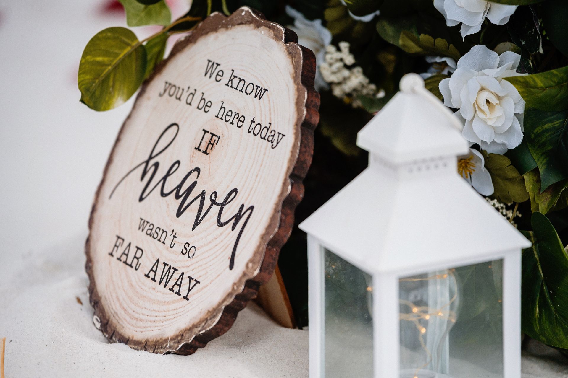 Rustic wooden sign with “Heaven” quote beside a white lantern and flowers