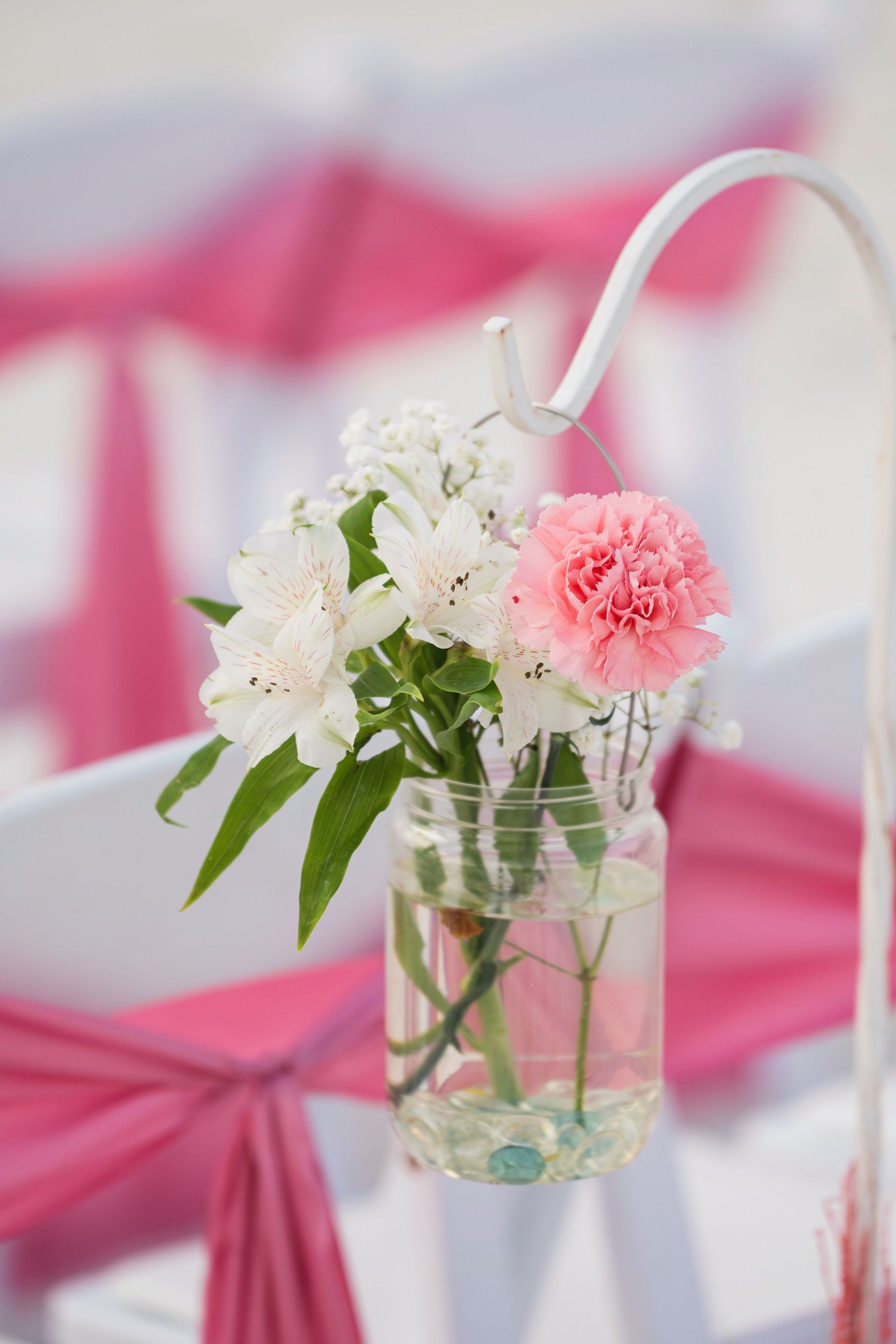 White and pink flowers in a glass vase on a pink-and-white table setting