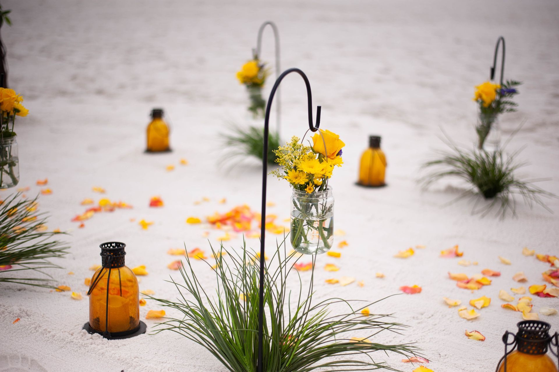 Amber lanterns and yellow flowers arranged on a white floor with scattered petals