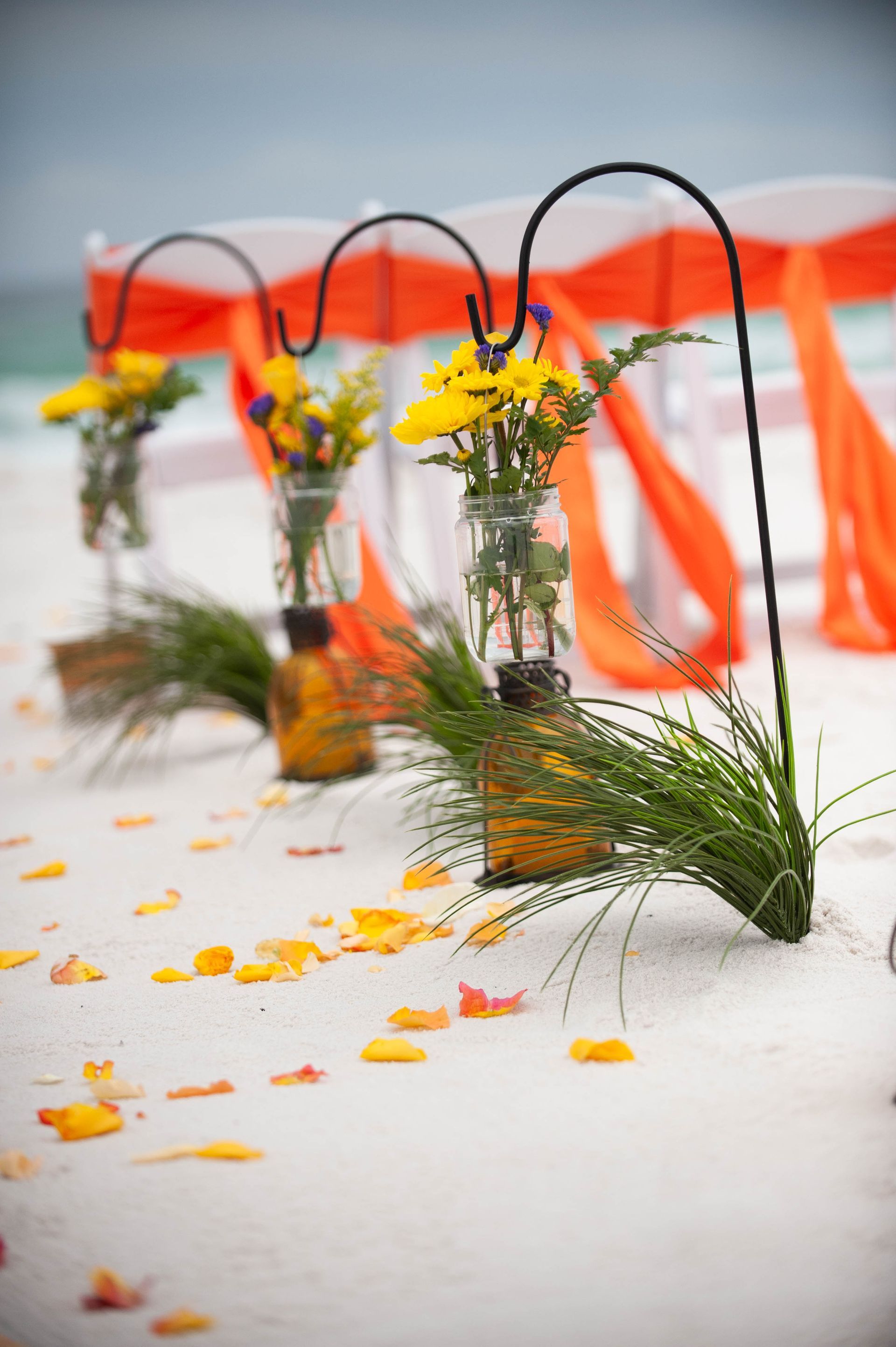 Rows of small flower bouquets with orange ribbons on a white surface, with petals scattered around