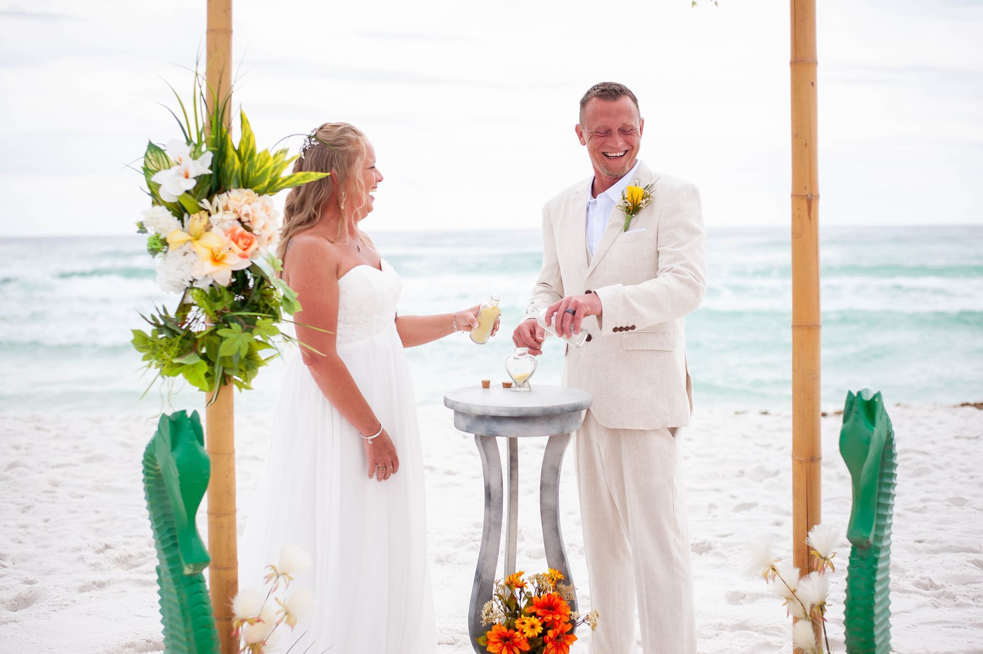 Bride and groom toast at a beach wedding under a floral arch