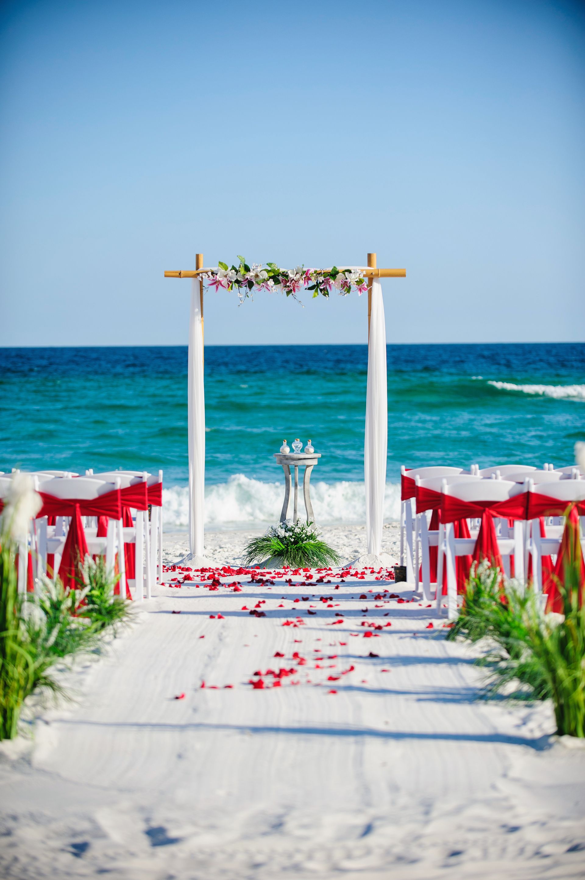 beach wedding altar and chairs with red sashes