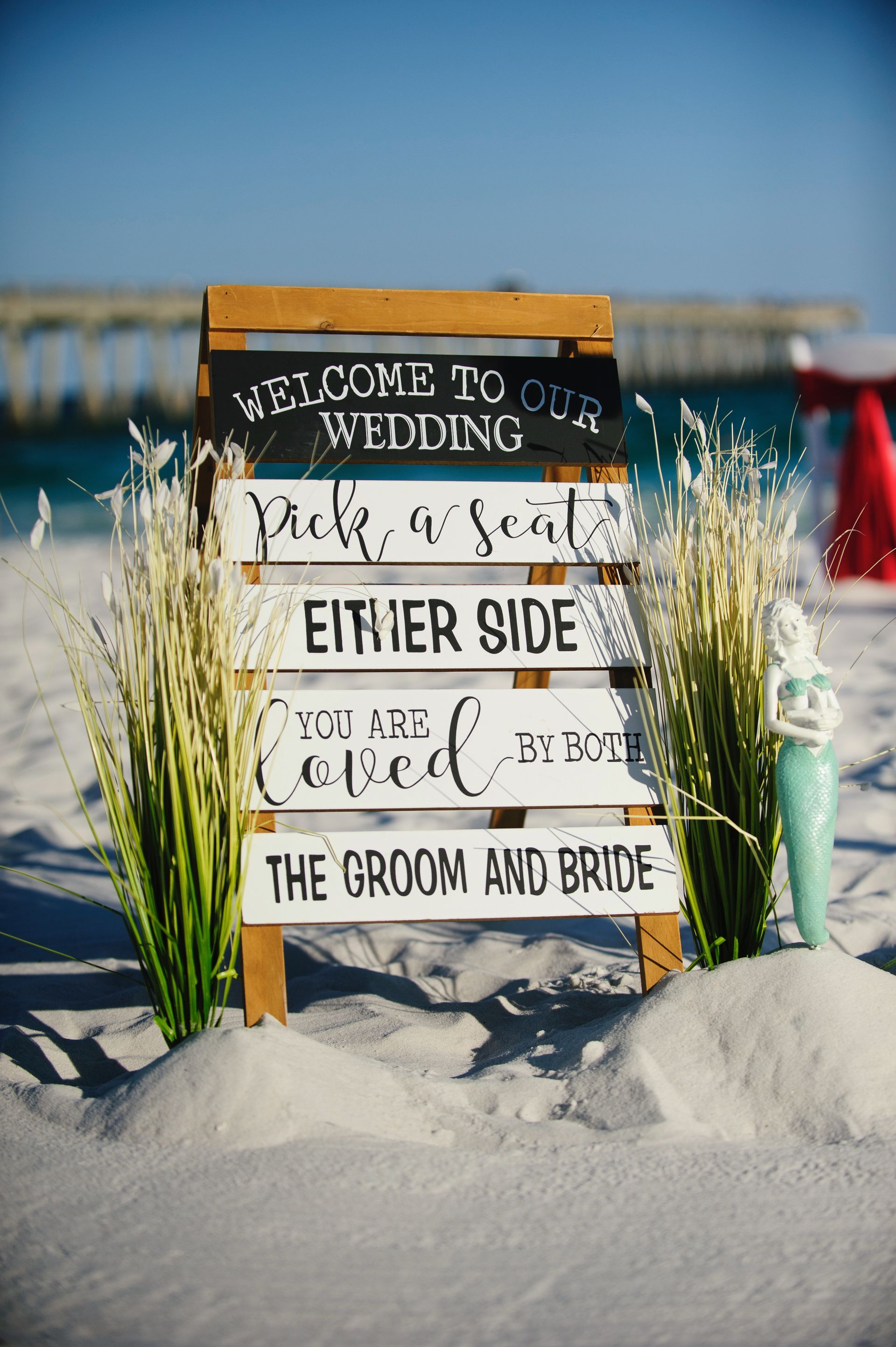 Beach wedding sign in snow reading “Welcome to our wedding” and “the groom and bride”