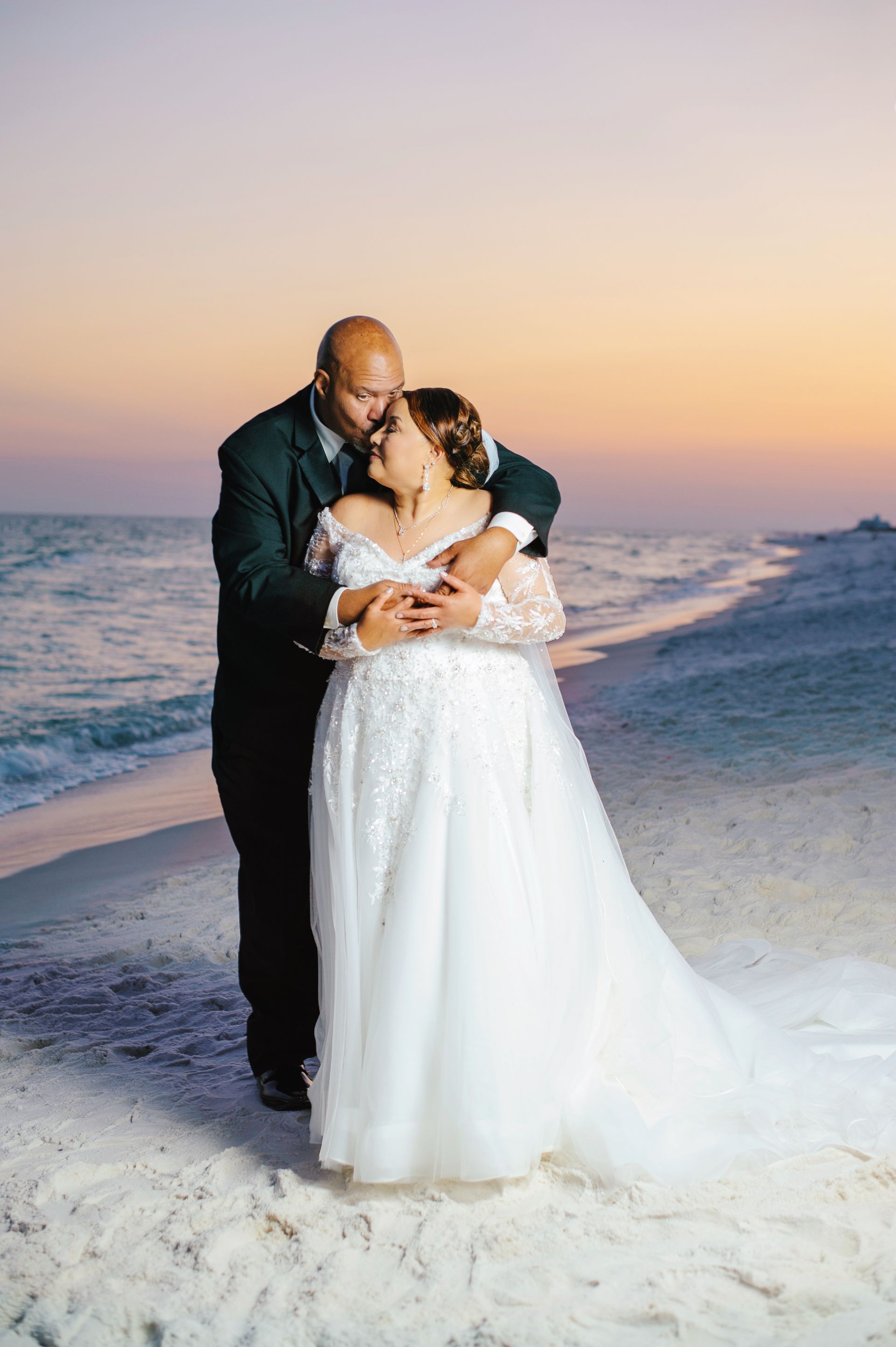 groom kissing bride on sunset during beach wedding