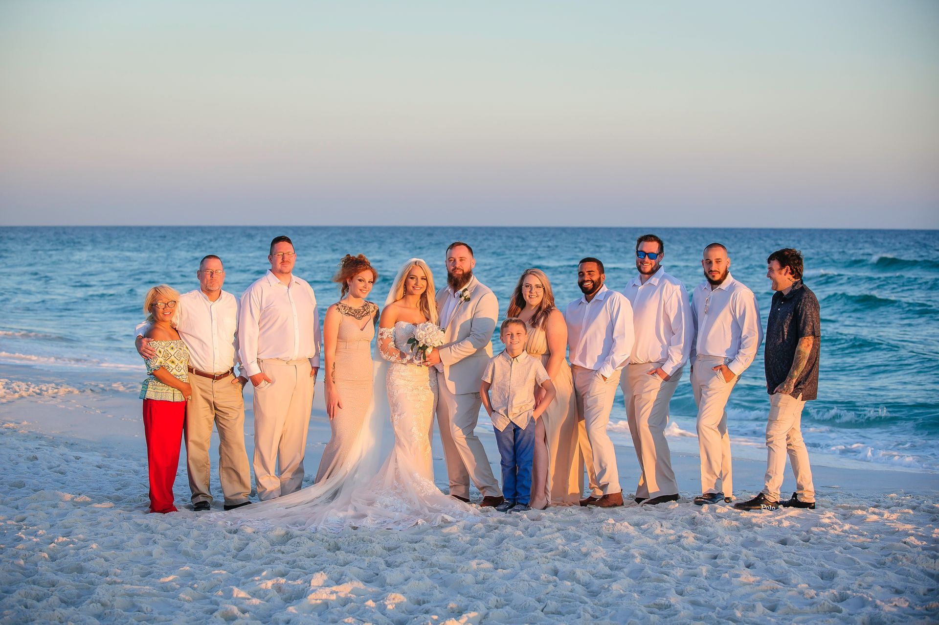 bride and groom with family on beach at sunset