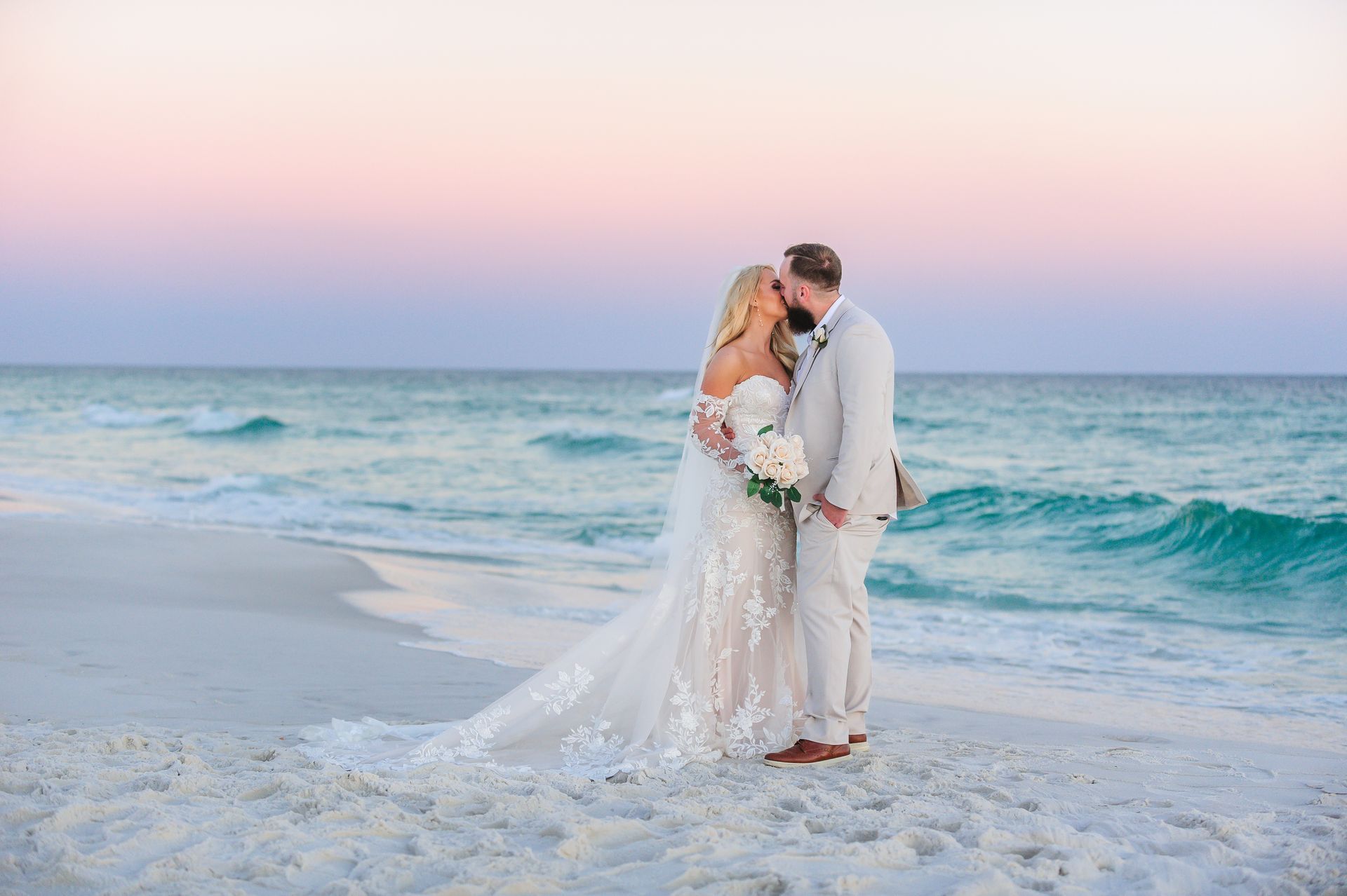 bride and groom kissing on beach at sunset