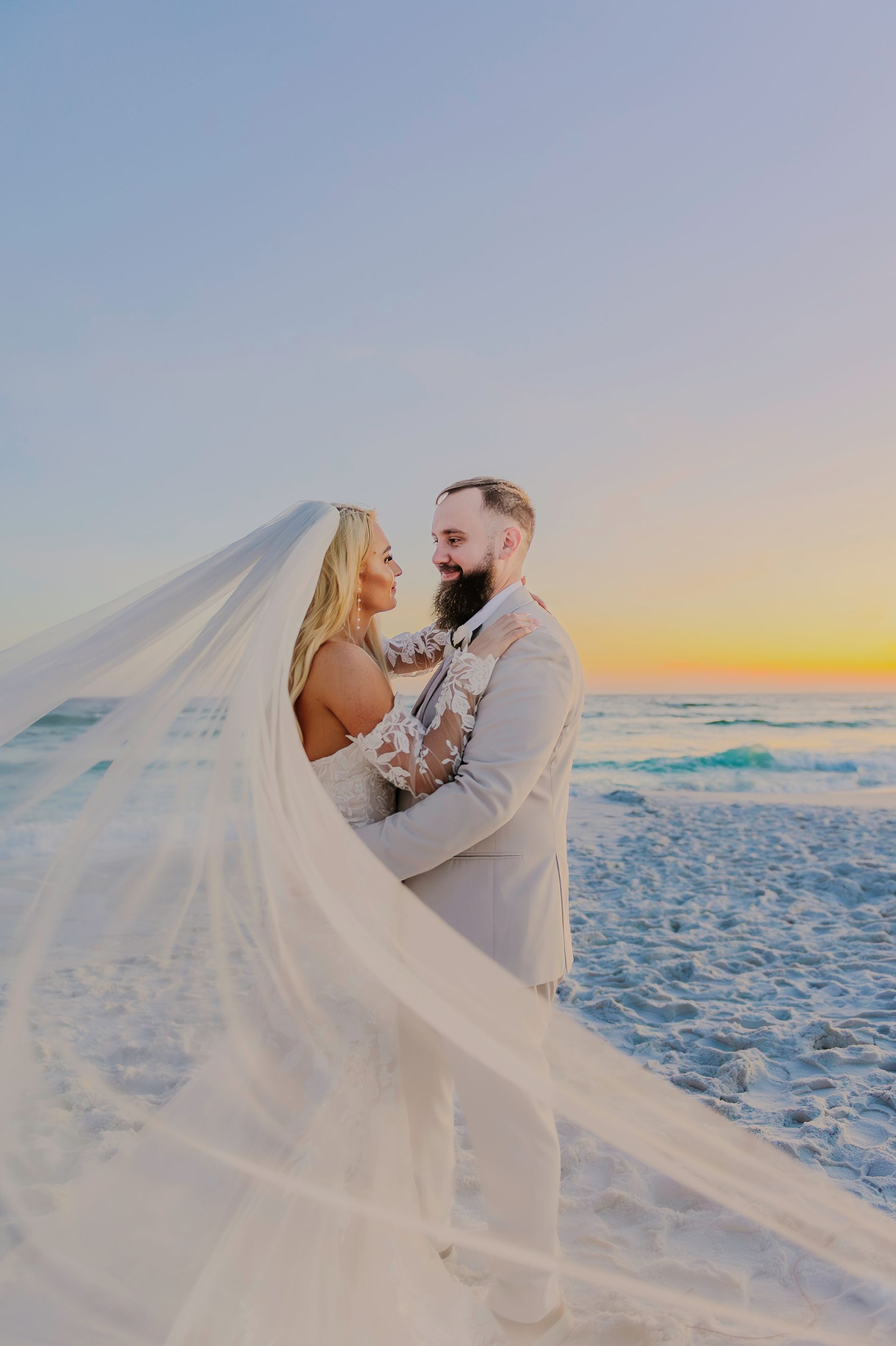 bride and groom embracing on the beach at sunset