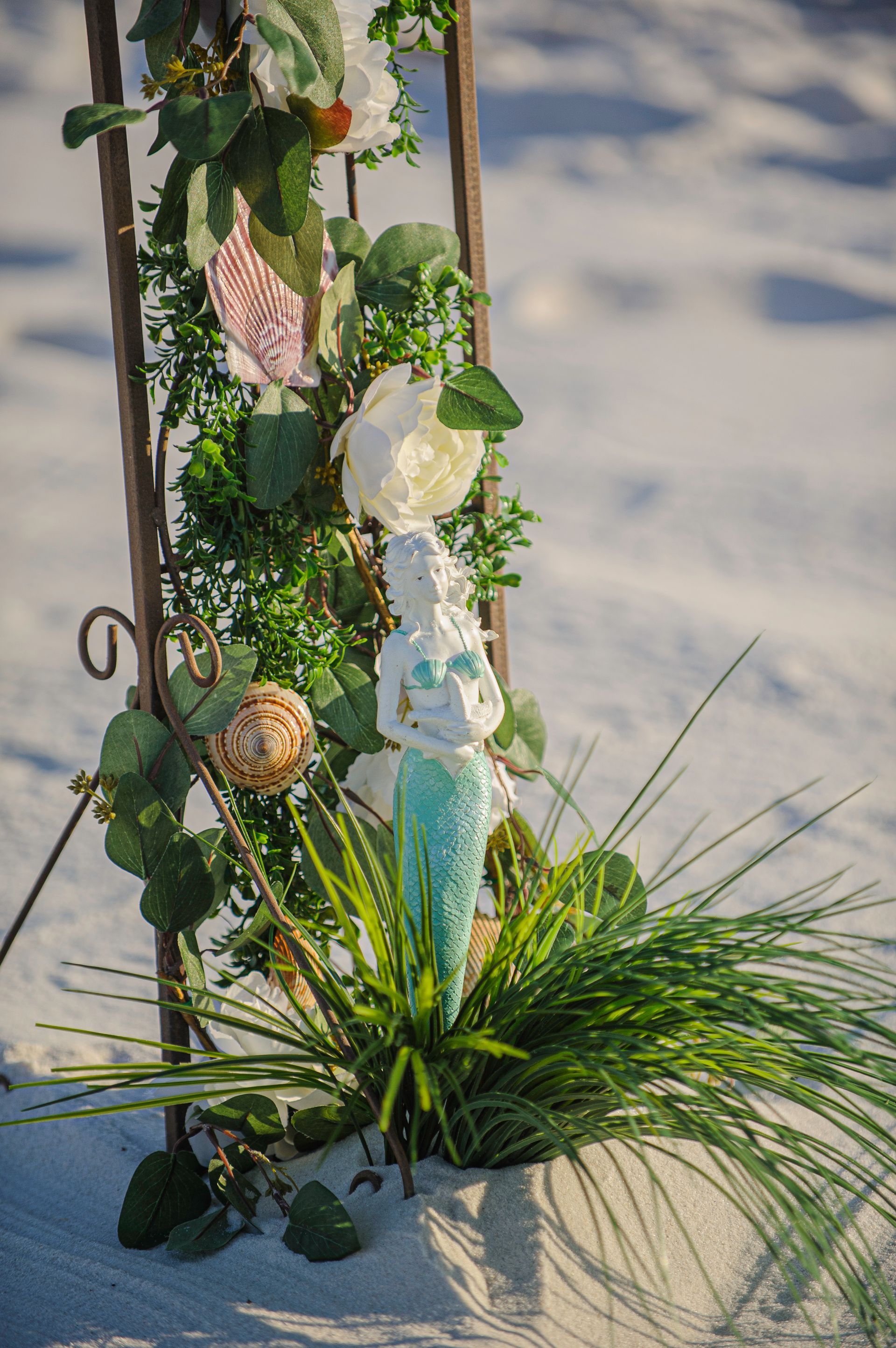 Decorated garden trellis with green vines, seashells, and a leafy plant at the base