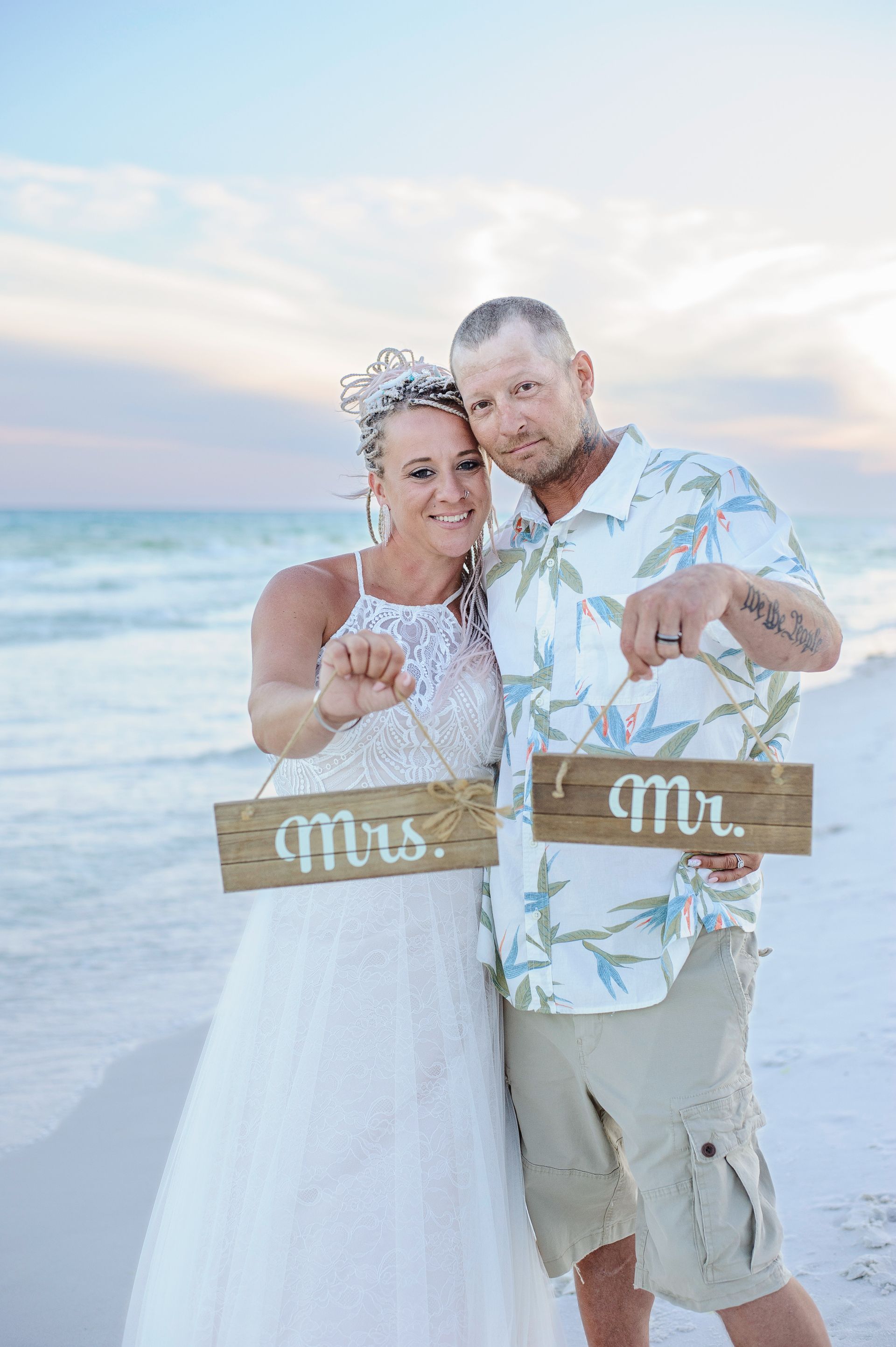 couple holding mrs. and mr. signs during beach wedding