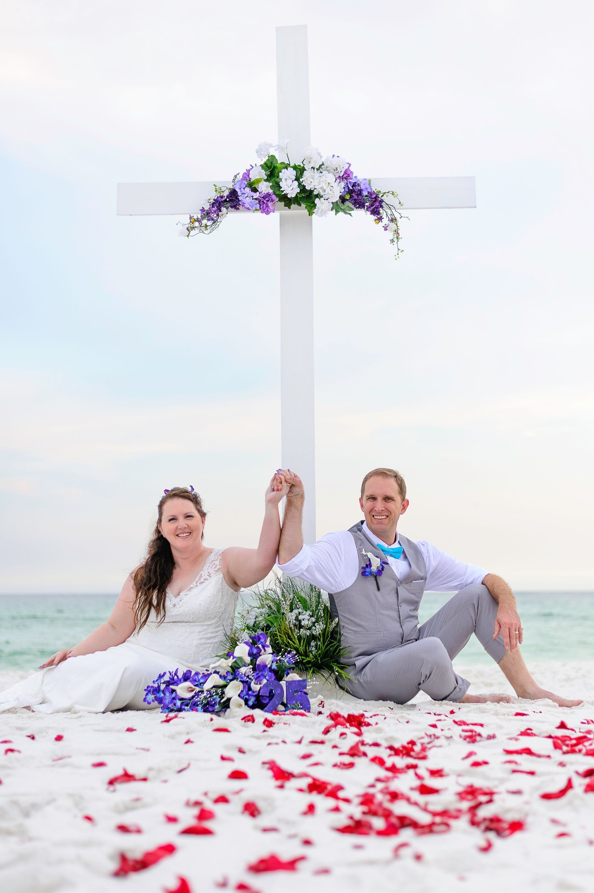 large white cross altar with purple and white flowers for beach wedding ceremony