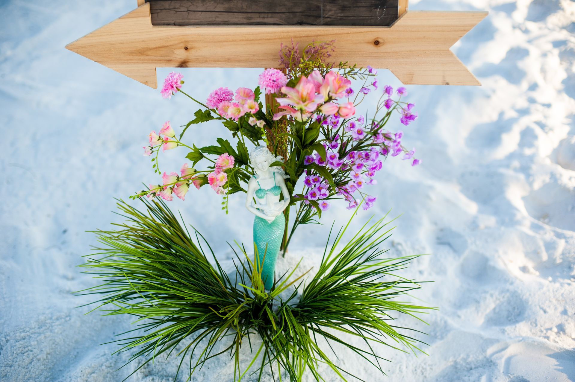 Bouquet of pink and white flowers in a glass vase on snow, with green pine needles around it