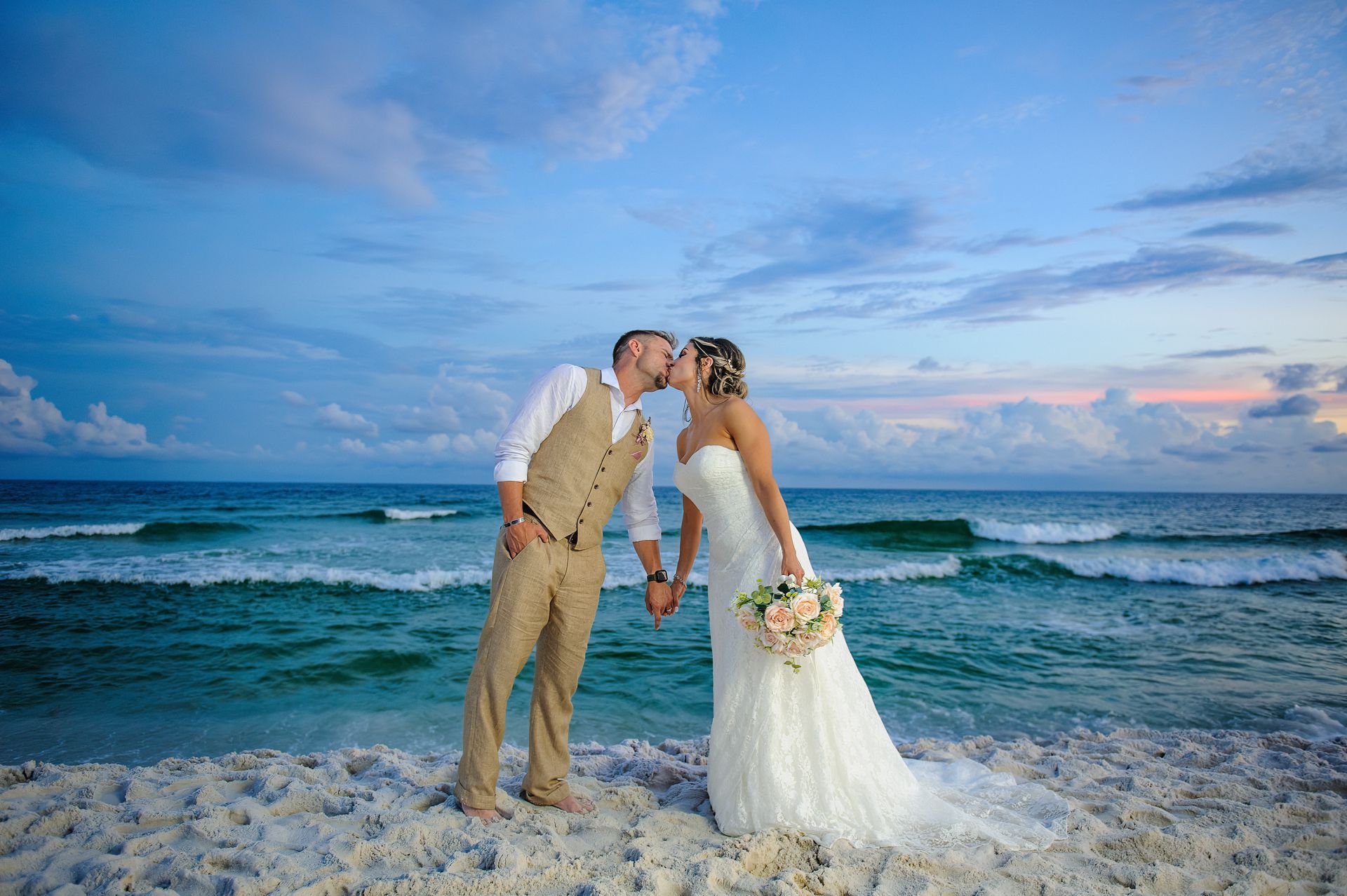 bride and groom kissing at sunset during beach wedding