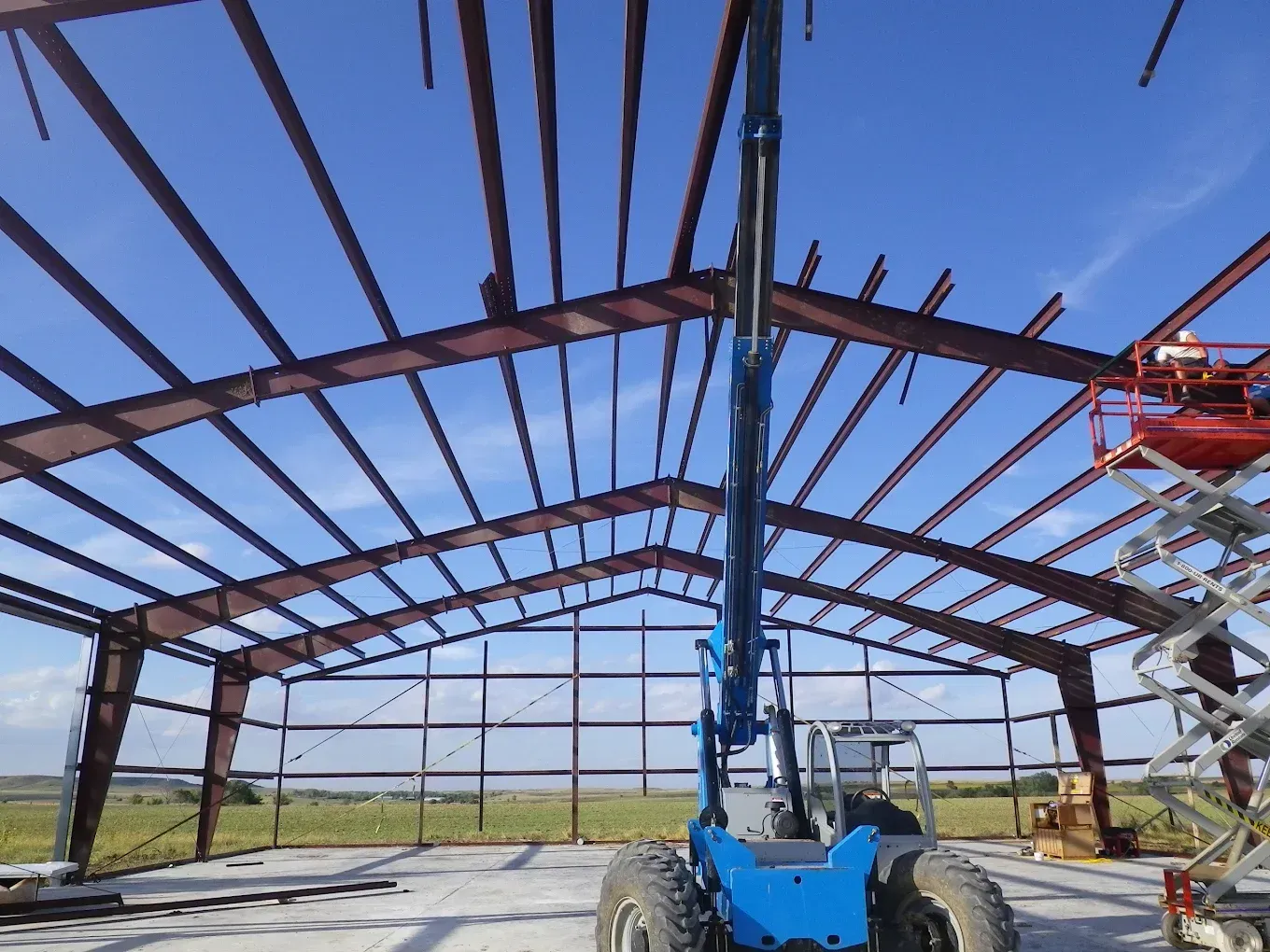 Construction worker in hard hat pointing at a building frame on a sunny day.