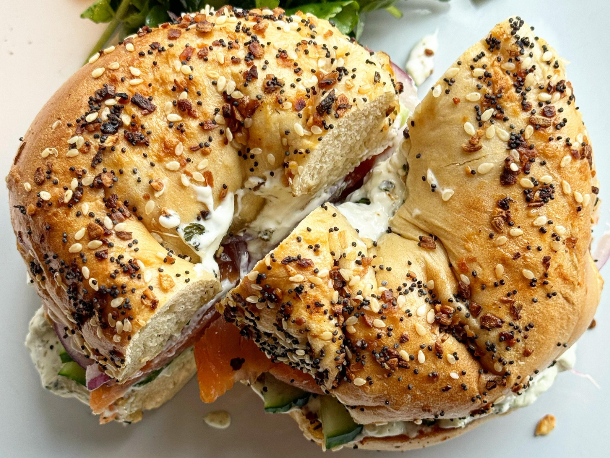 A bagel sandwich is cut in half on a white plate.