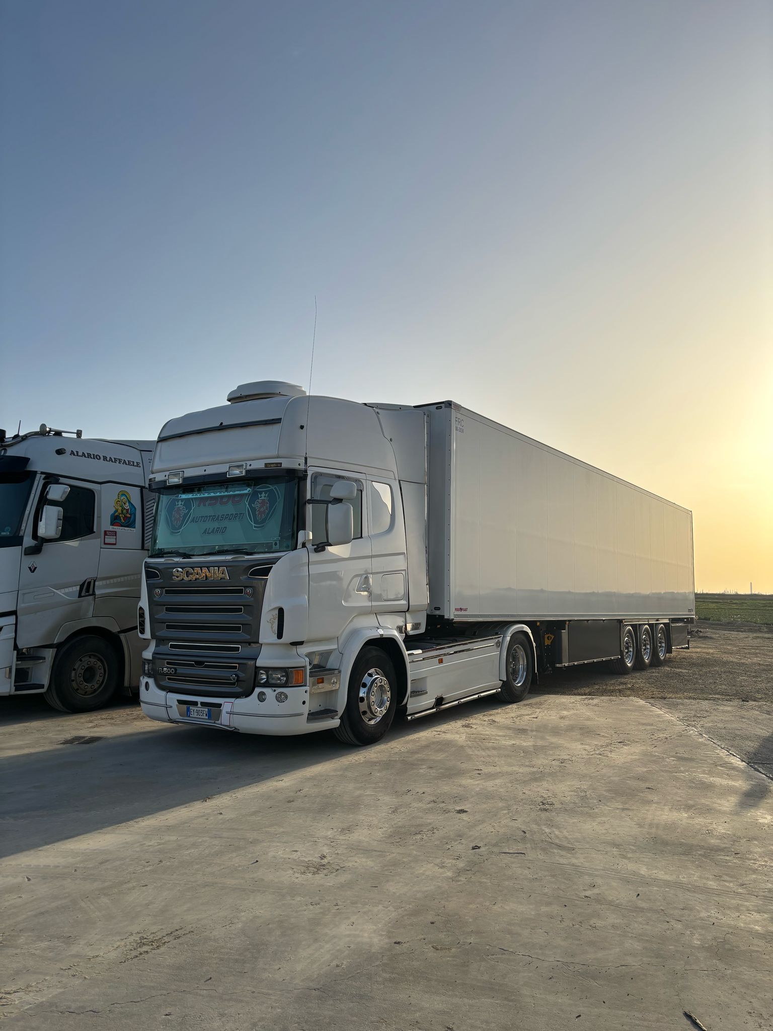 Due camion bianchi sono parcheggiati uno accanto all'altro in un parcheggio.